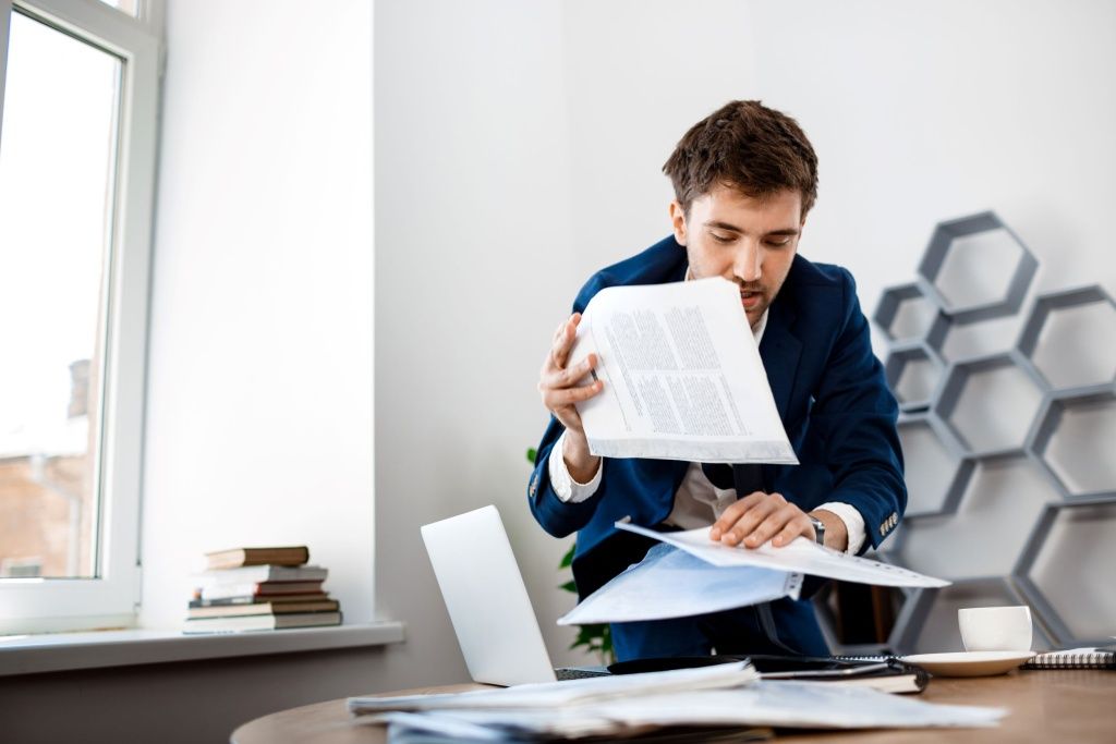 absentminded-young-businessman-rummaging-papers-office-background.jpg